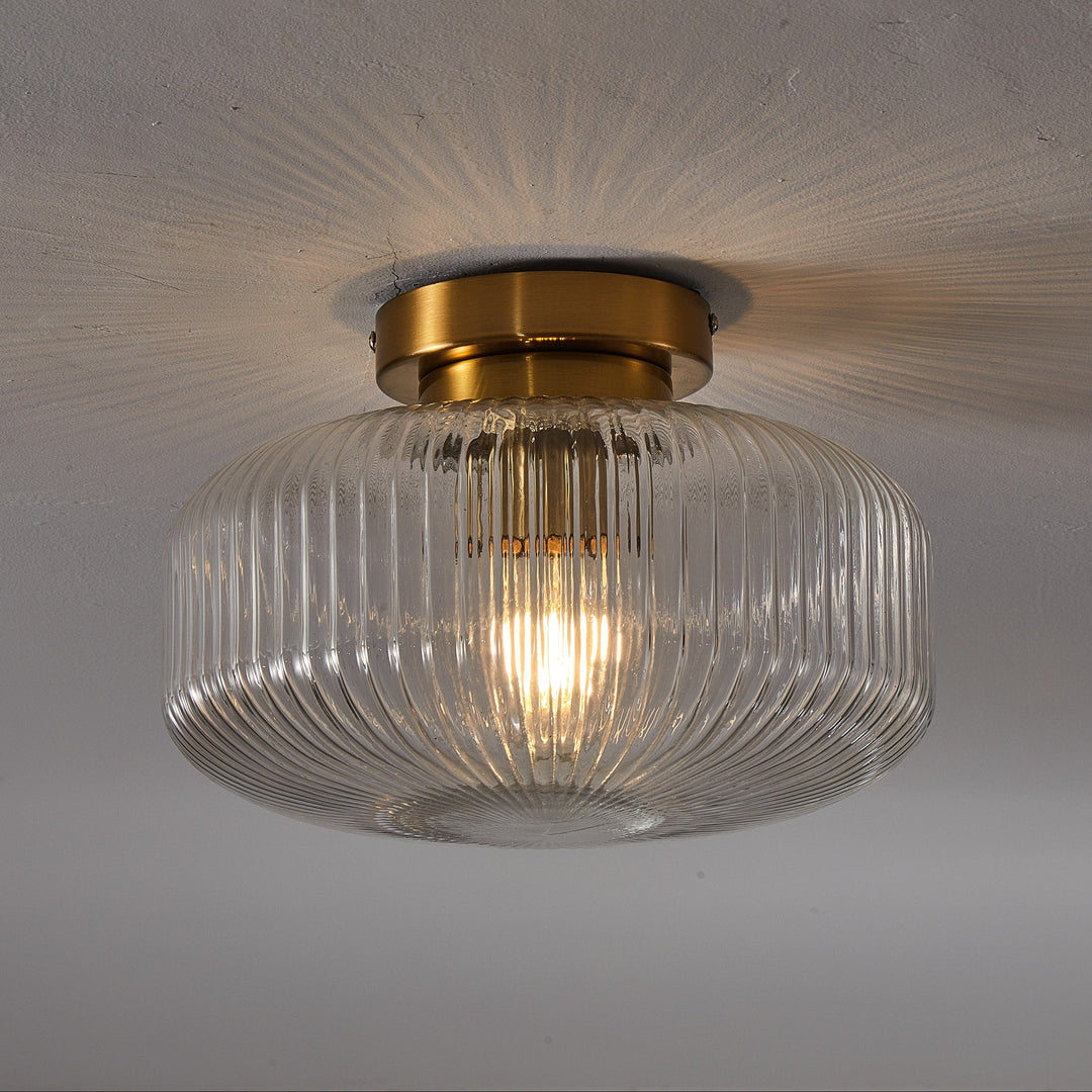 Ceiling light fixture with glass shade and gold trim on a plain background