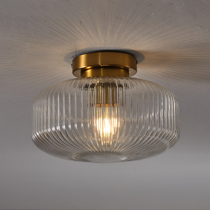 Ceiling light fixture with glass shade and gold trim on a plain background