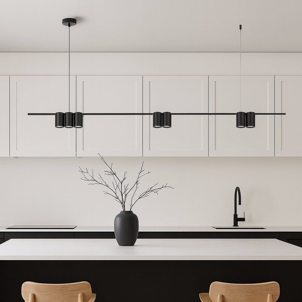 Nordic style kitchen with a modern black bar pendant light hanging above a white island, featuring minimalist black and white cabinetry and natural wood chairs.
