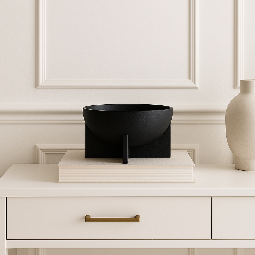Black decorative bowl on stacked books atop a white console table with gold handle.