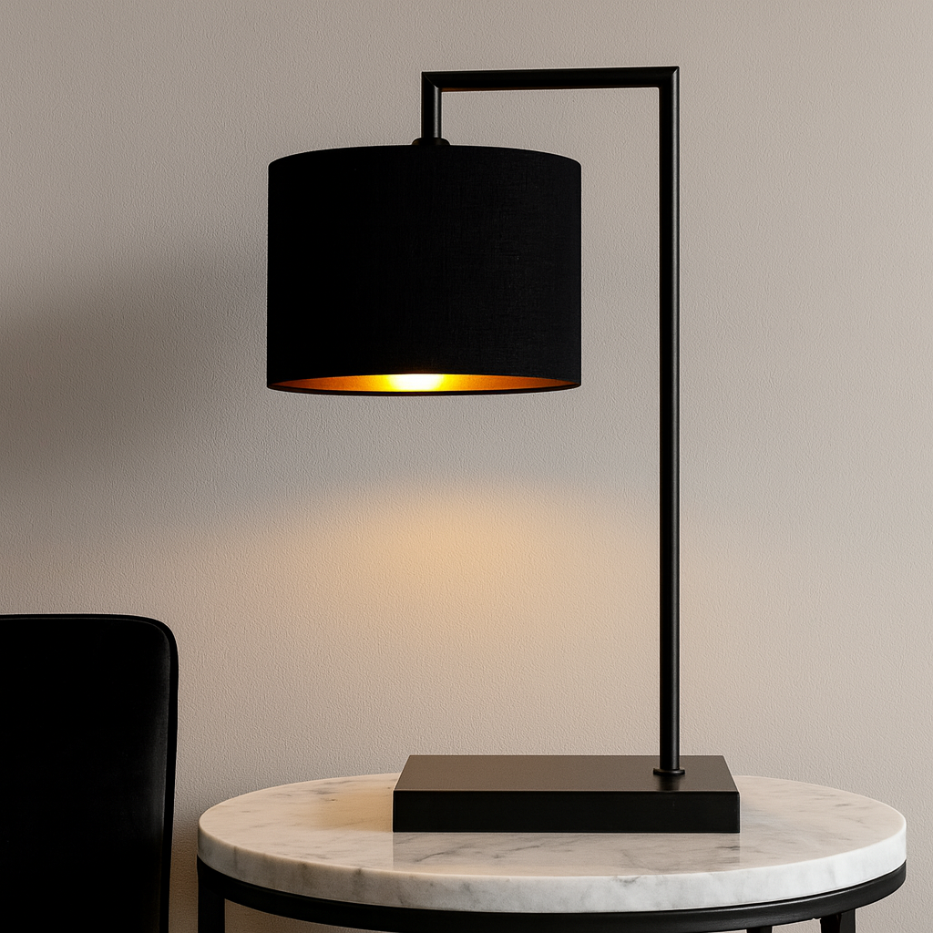 Luxury black table lamp with 25cm black shade and gold lining on a round marble side table against a neutral wall.