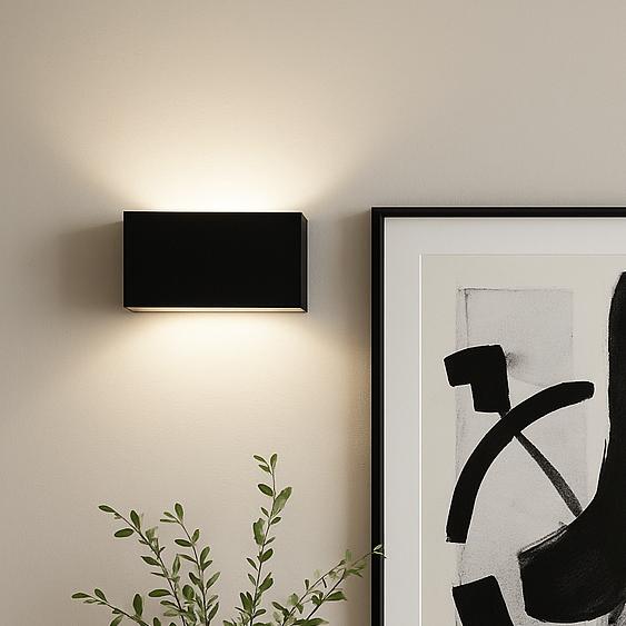 Black rectangular wall light with subtle glow above console and monochrome artwork.