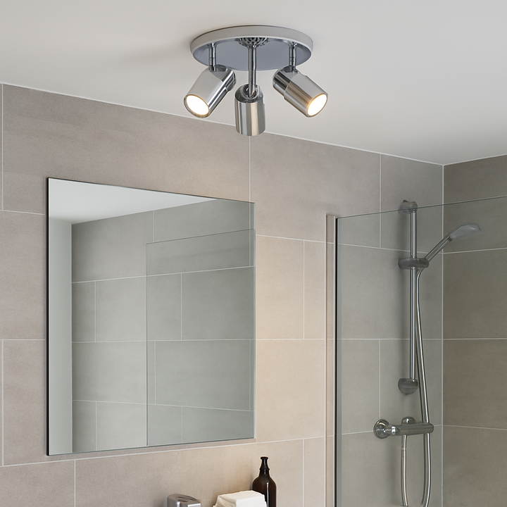 Chrome 3 light bathroom spotlight on ceiling in a modern bathroom with tiled walls, frameless mirror and glass shower enclosure