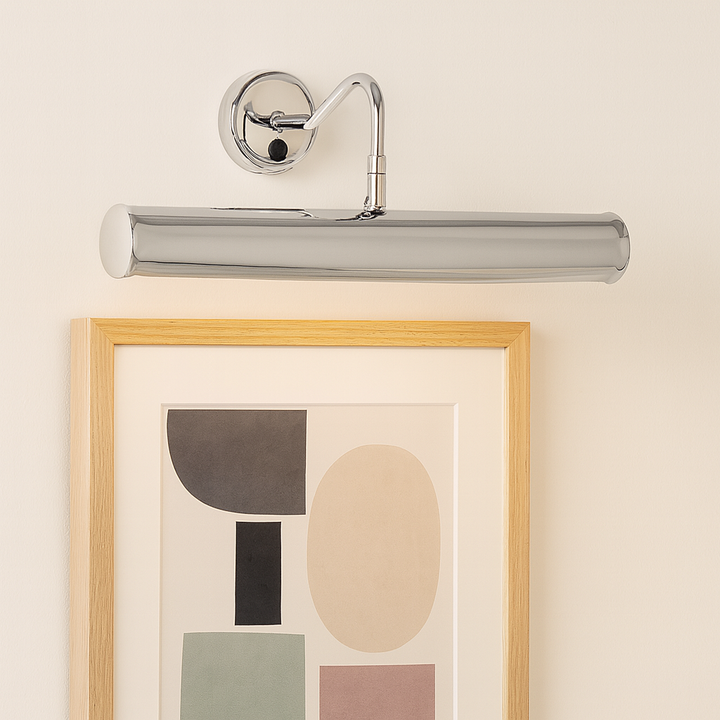 Polished chrome picture wall light illuminating framed abstract artwork on a neutral wall