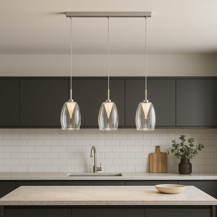 Modern luxury kitchen with marble island and three clear glass pendant bar lights hanging evenly from a ceiling, styled with dark cabinetry and neutral decor