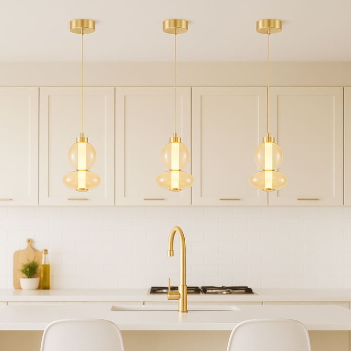 Modern cream kitchen with gold accents featuring three 20cm amber glass pendant lights hanging proportionally over a small island.