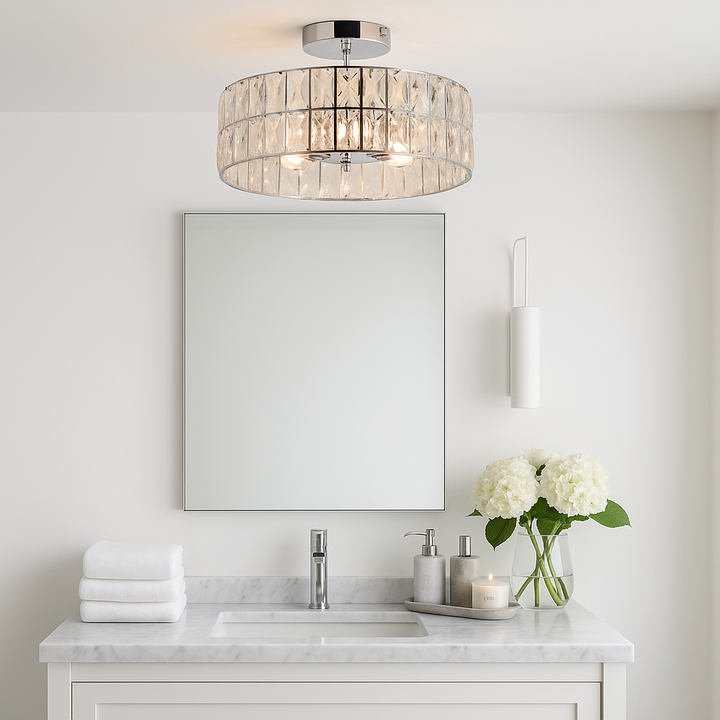 Crystal drum flush ceiling light in a luxury bathroom with white walls, marble vanity, stacked towels, flowers, candle, and chrome accessories.