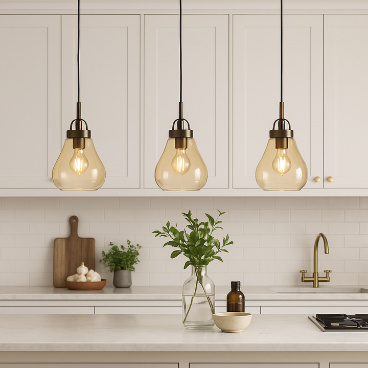 Amber glass pendant lights with bronze fittings above modern white kitchen island with shaker cabinets.