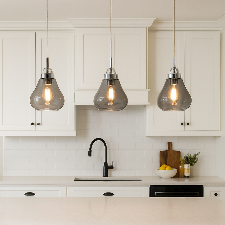 Smoked glass pendant lights with chrome detail above modern white kitchen island with black accents