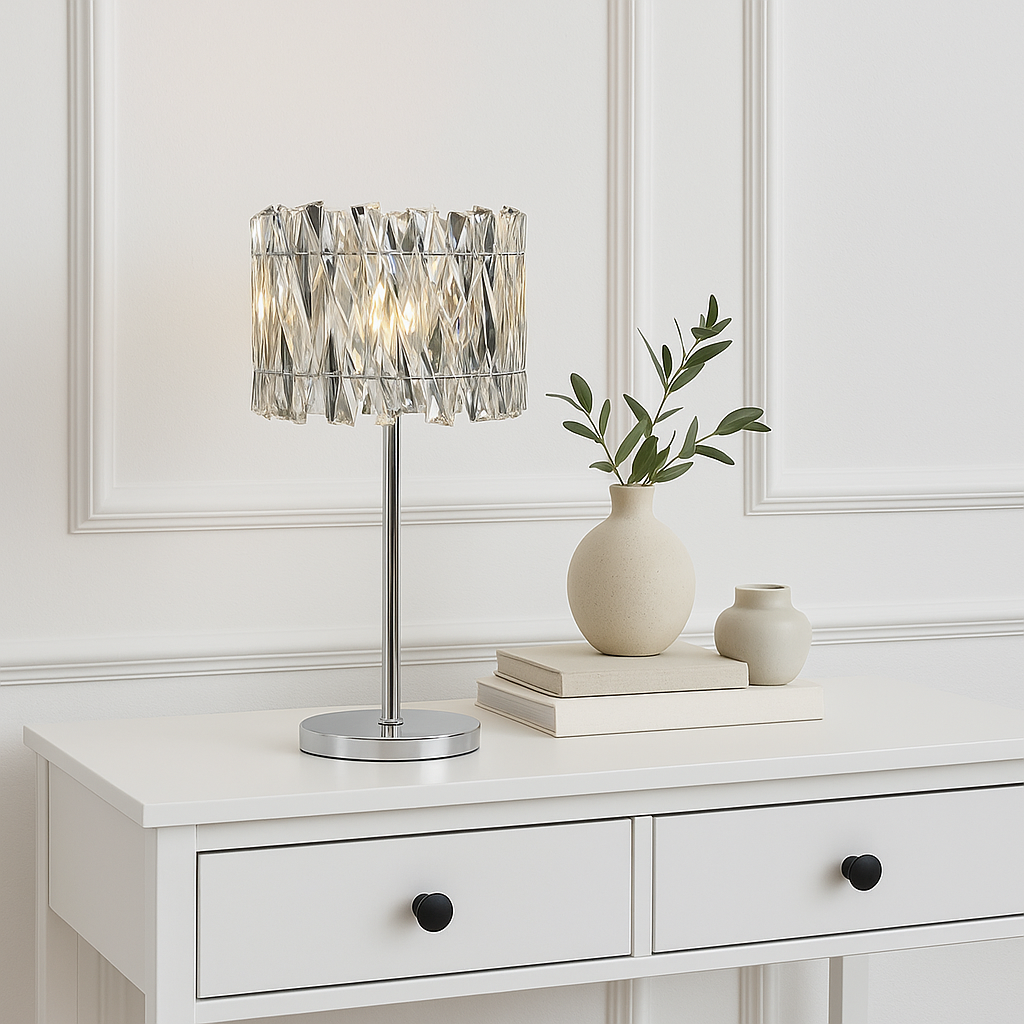 Devonport crystal table lamp on white console with black handles, styled with neutral books and ceramic vases against white panelled wall.