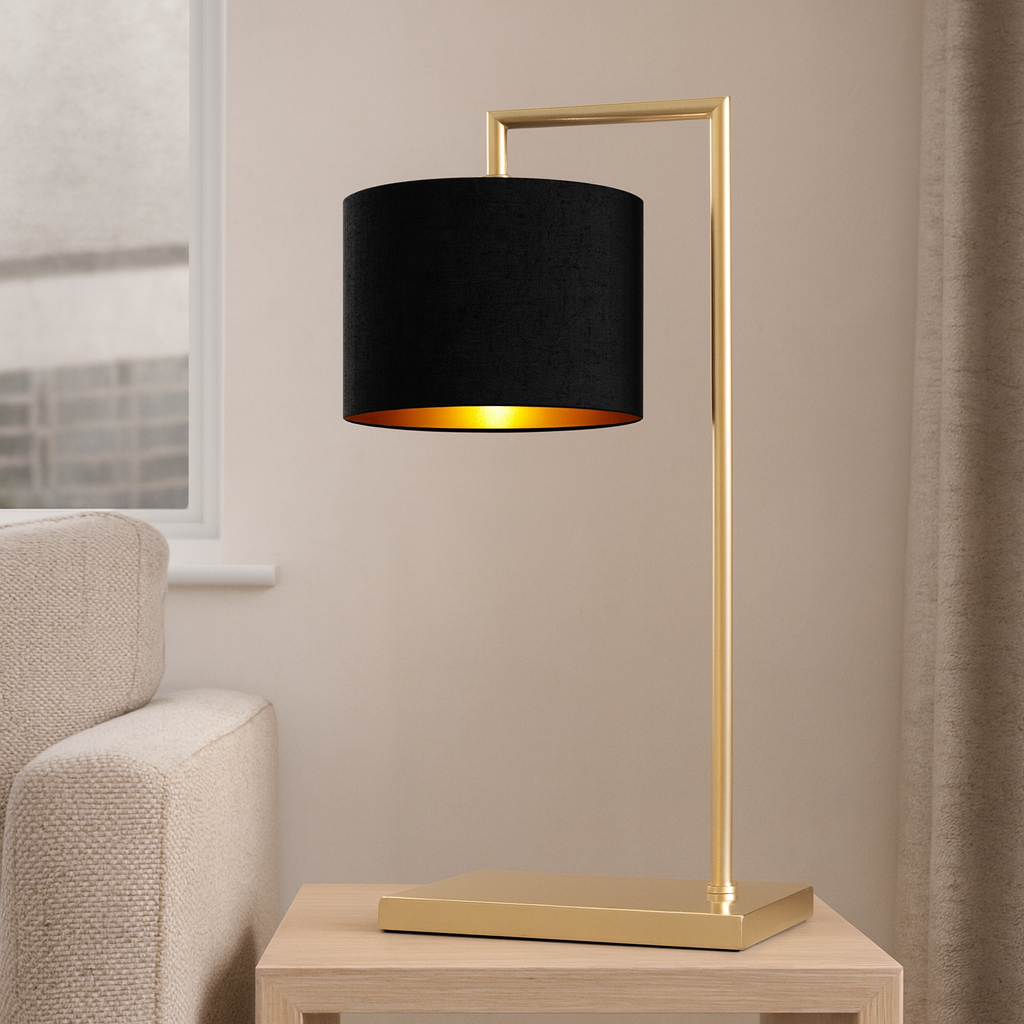 Lifestyle image of the Fairview gold table lamp with a 25cm black fabric shade and gold lining, 59cm total height, styled on a wooden side table beside a neutral sofa.