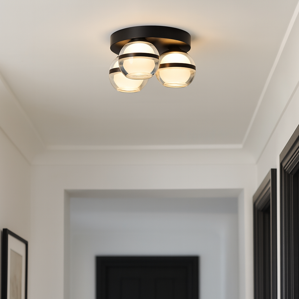 Small black flush ceiling light with three glass globes styled in a modern hallway with black highlights and neutral walls.