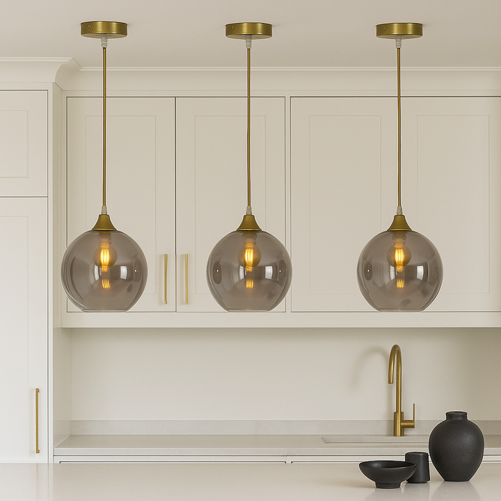 Luxury kitchen with three Irvine gold smoked glass pendant lights hung above a white island, spaced evenly with gold cabinet accents and minimal black styling pieces.