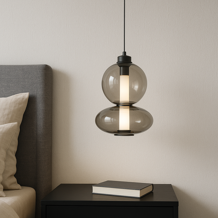 Modern glass mini pendant bedside light with smoke finish hanging above a black cabinet in a neutral bedroom setting.