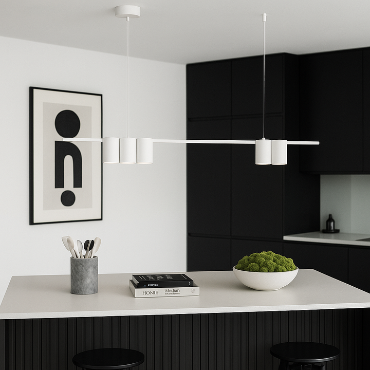 Nordic style black kitchen with white bar pendant light above island, simple artwork on wall, and decorative bowl filled with green moss.
