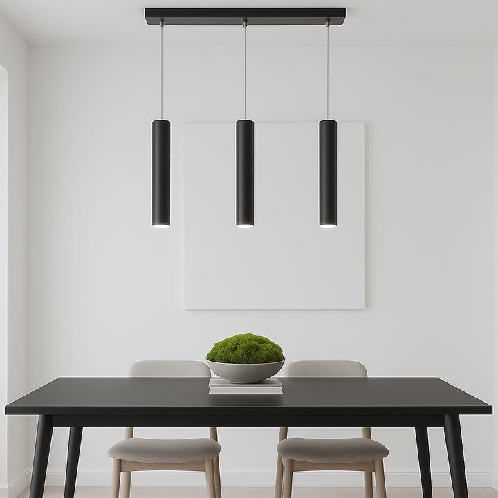 Pictou black 3 light cylinder pendant, 45cm wide, styled above a modern black dining table with moss bowl on stacked books.