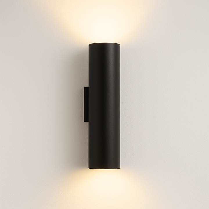 Pictou black cylindrical wall light with warm glow on white background