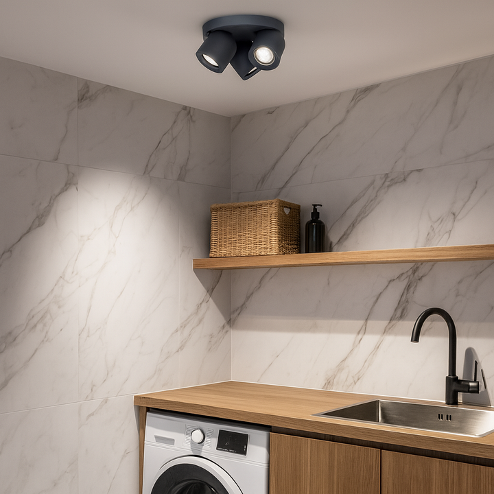 Rosebery Grey 3 Light Round Spotlight mounted on the ceiling of a modern home office with marble wall tiles, oak shelving, washer, and stainless steel sink.