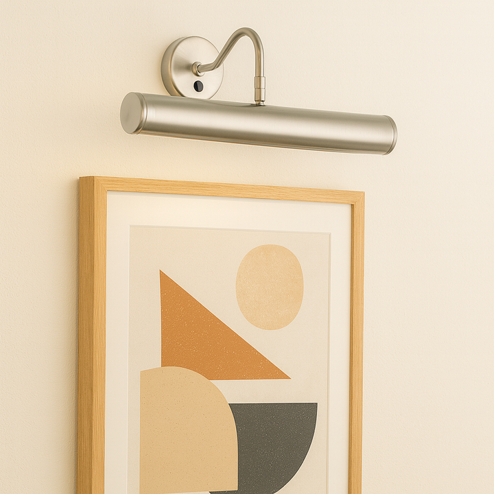 Stainless steel picture wall light illuminating framed abstract geometric artwork on a neutral wall