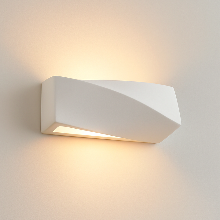 Vancouver Small ceramic wall light in white, featuring a modern twisted design that casts warm up and down lighting on a white wall.
