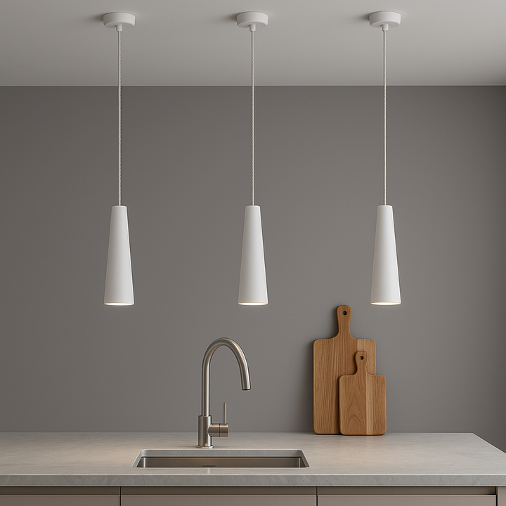 Three white cone pendant lights hung above a modern kitchen island with wooden chopping boards styled against a neutral wall.