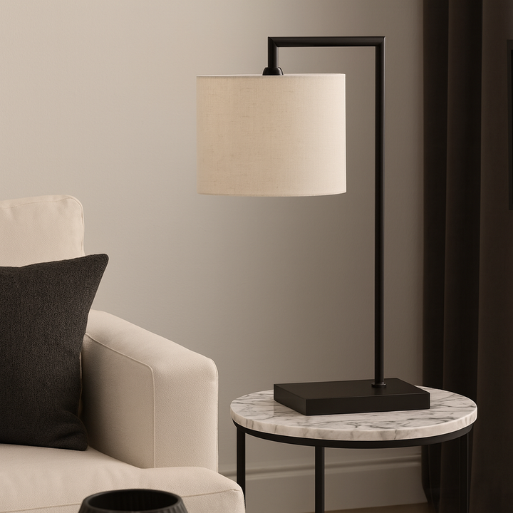 Modern black table lamp with 25cm white fabric shade on a round marble side table beside a neutral sofa in a luxury living room.