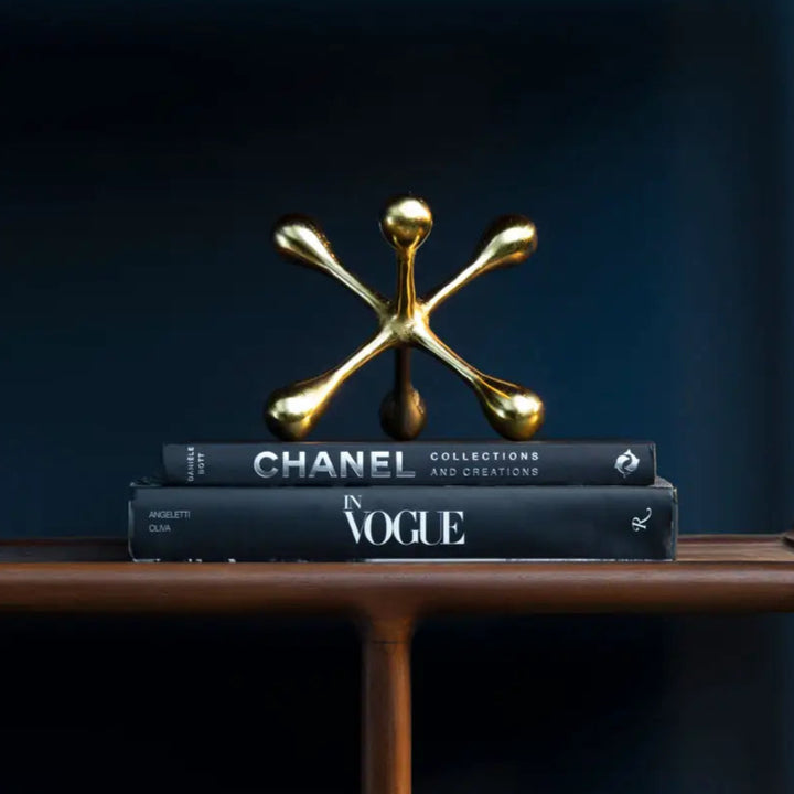 Gold decorative item on top of Chanel and Vogue books against a dark background