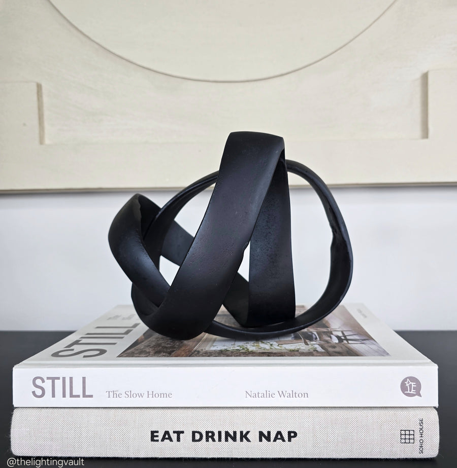 Black abstract sculpture on a stack of books with a neutral background