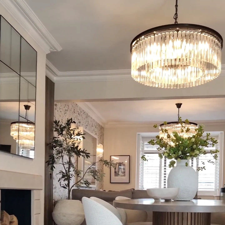 Chandelier hanging in a living room with a fireplace and decorative elements.