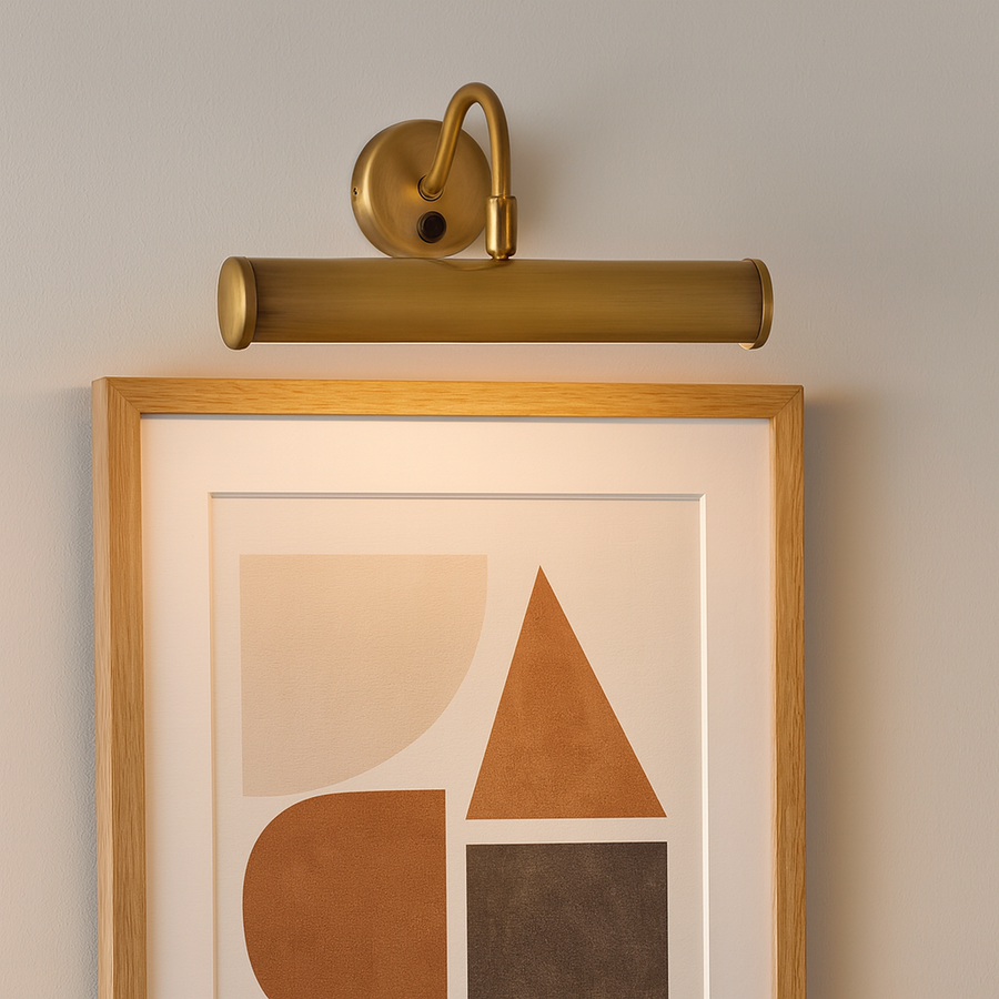 Brass picture wall light illuminating framed abstract geometric artwork on a soft grey wall