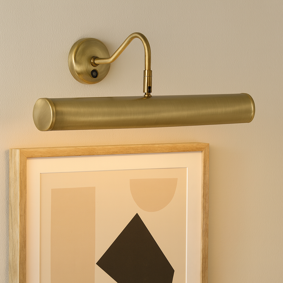 Brass picture wall light illuminating modern geometric artwork in a natural wood frame