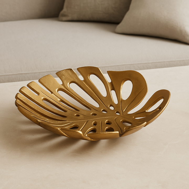 Luxury antique gold monstera leaf decorative dish styled on a light neutral marble surface in modern home décor