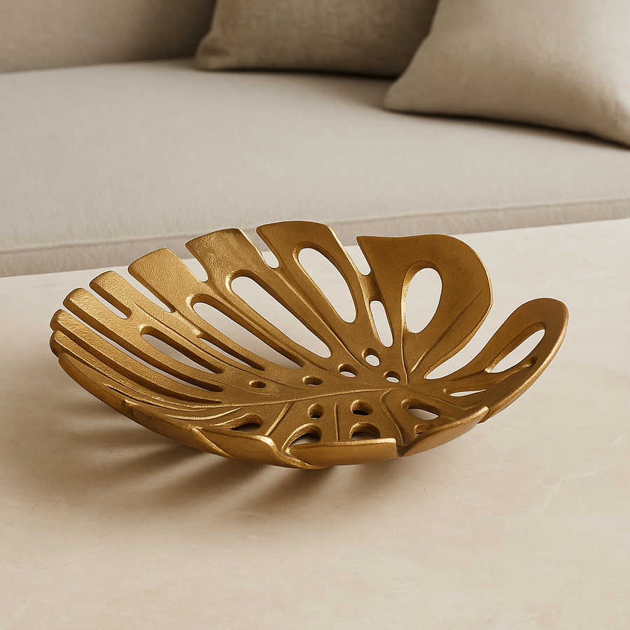 Luxury antique gold monstera leaf decorative dish styled on a light neutral marble surface in modern home décor