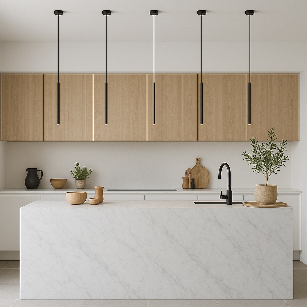 Scandinavian style kitchen with white marble island, light wood cabinets, black tap, and five slim black pendant lights hanging above.