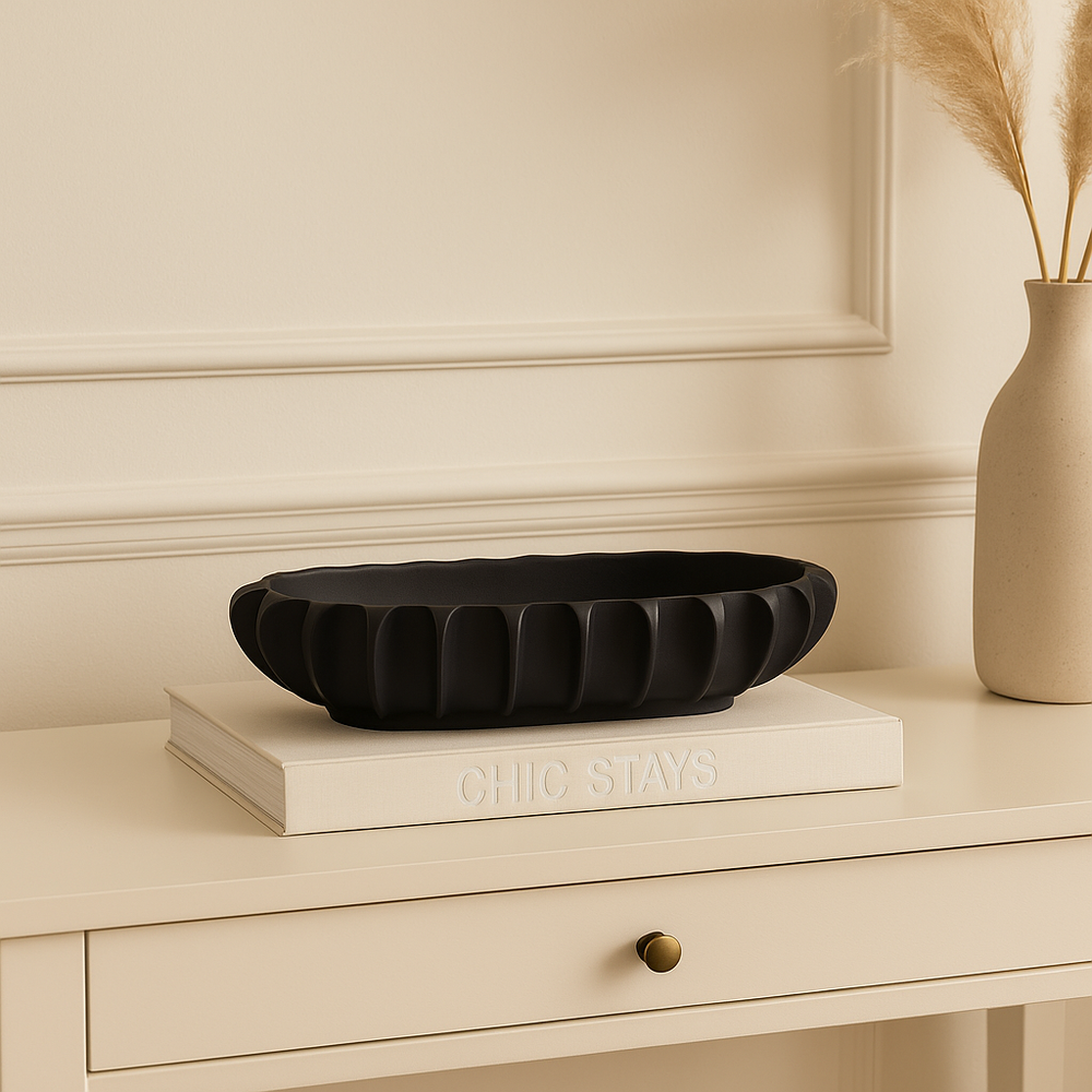 Empty black fluted bowl on a large book and white console table