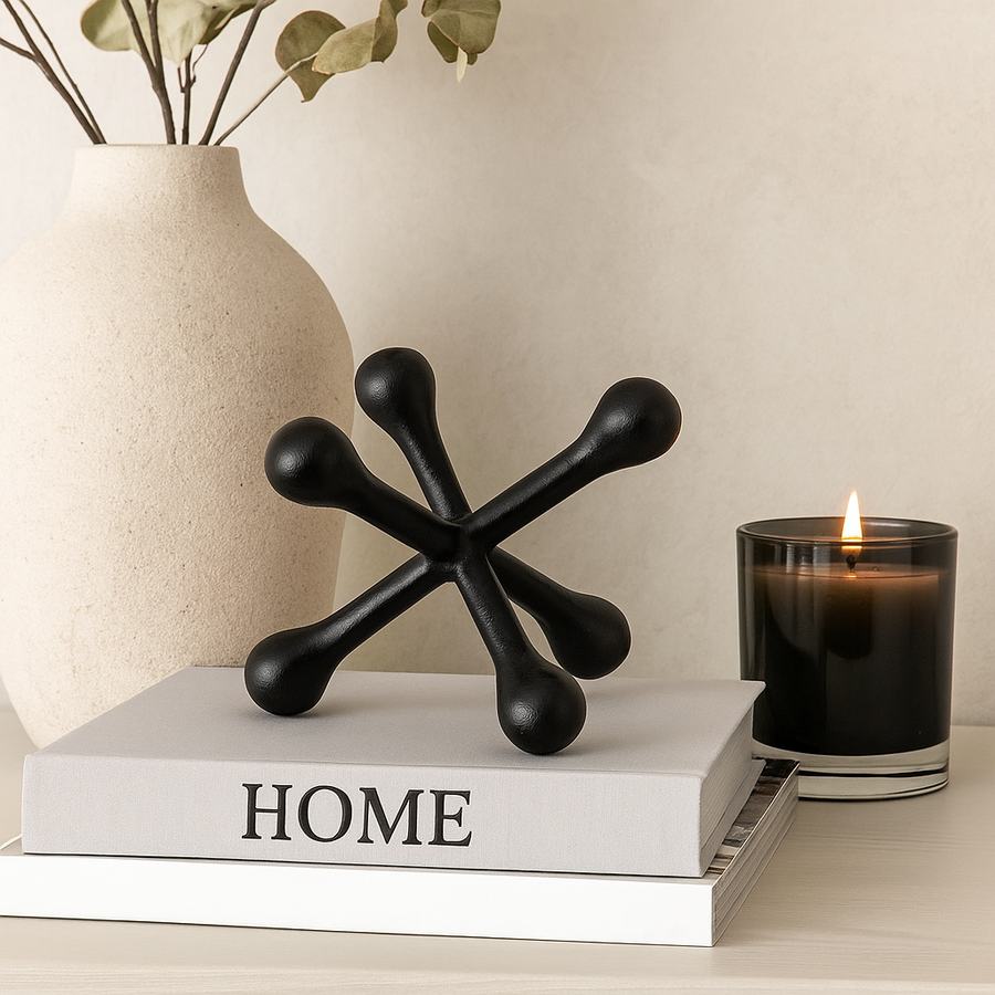 Luxury black metal jack sculpture styled on books with vase and candle on a modern sideboard.