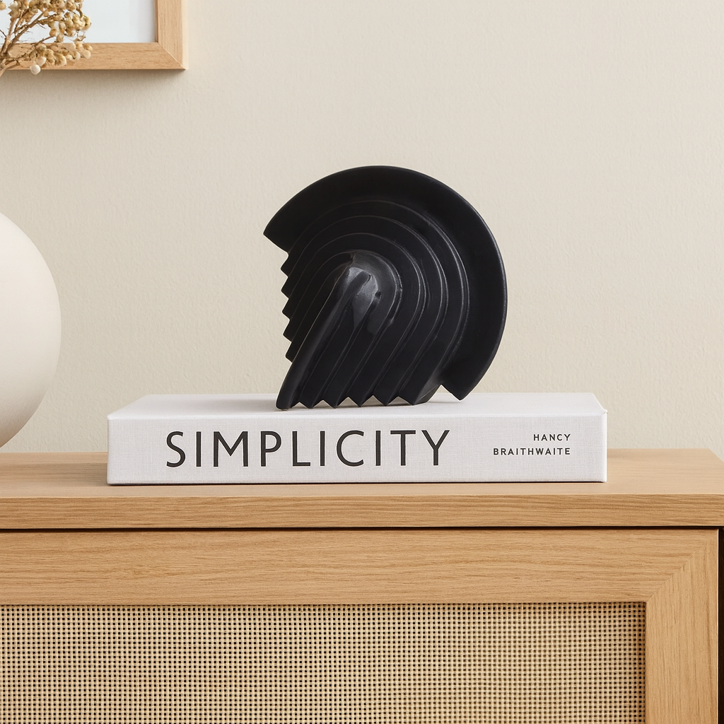 Black geometric sculpture styled on a Nordic media wall unit, placed on a modern coffee table book for a minimalist home décor look.