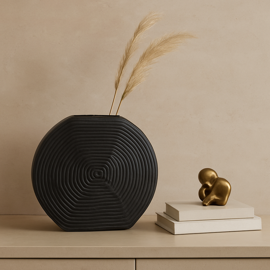 Luxury black textured metal vase styled on a light-toned console with books and subtle brass accents in a modern neutral home setting
