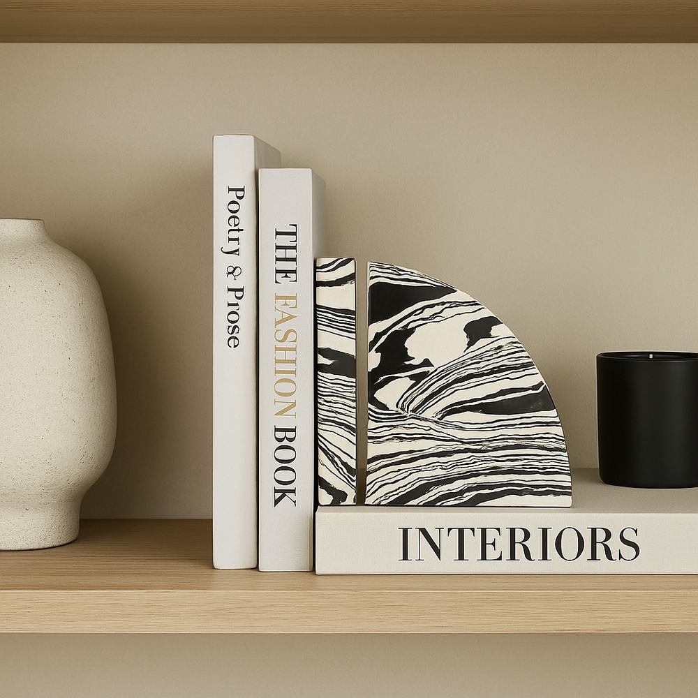 Black and white marble effect bookends styled on a Nordic wooden shelf with modern books, vase, and candle.