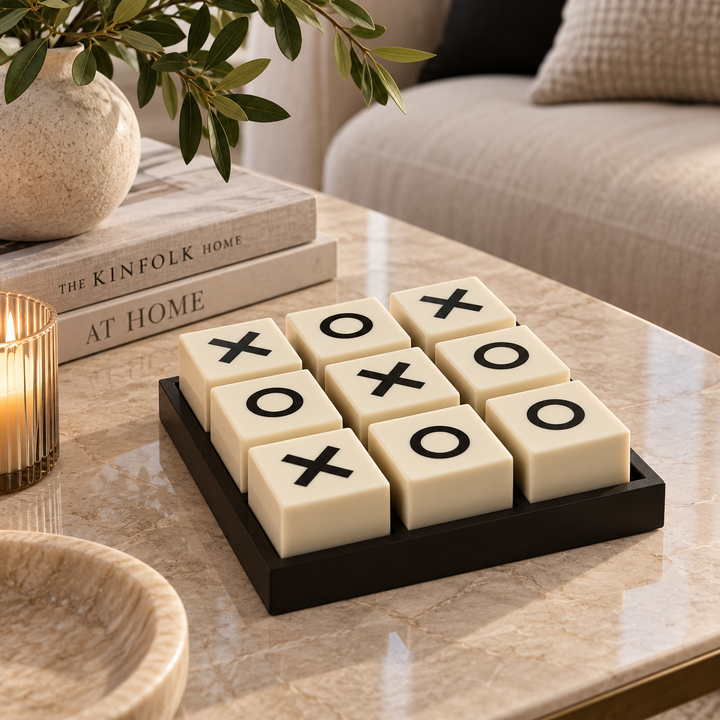 Black and white noughts and crosses decorative game set styled on a marble coffee table in a modern living room with neutral home accessories.
