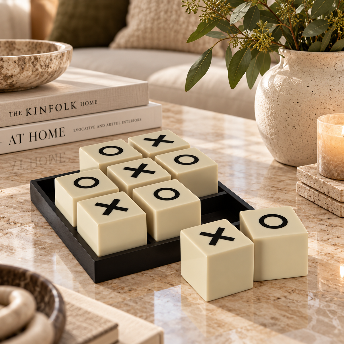 Black and white noughts and crosses decorative game with ivory blocks and black tray, styled on a marble coffee table in a contemporary living room.