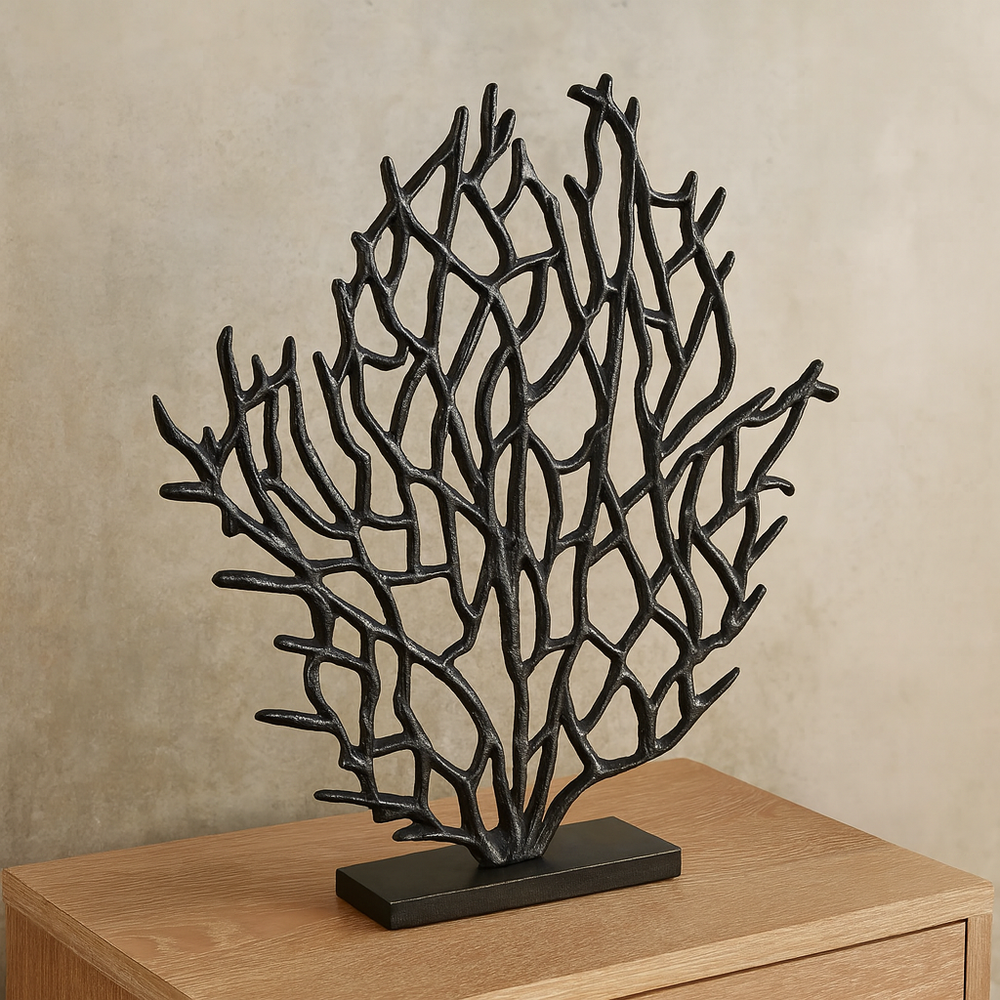 Decorative black coral sculpture on a wooden surface with a beige wall background
