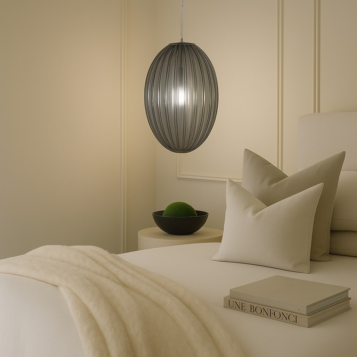 Luxury bedroom interior with Braga smoked glass pendant light, neutral bedding, black bowl with moss and stacked books