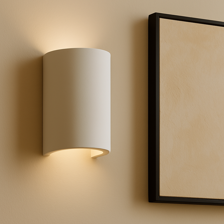 Beige wall sconce on a beige wall with a framed picture.