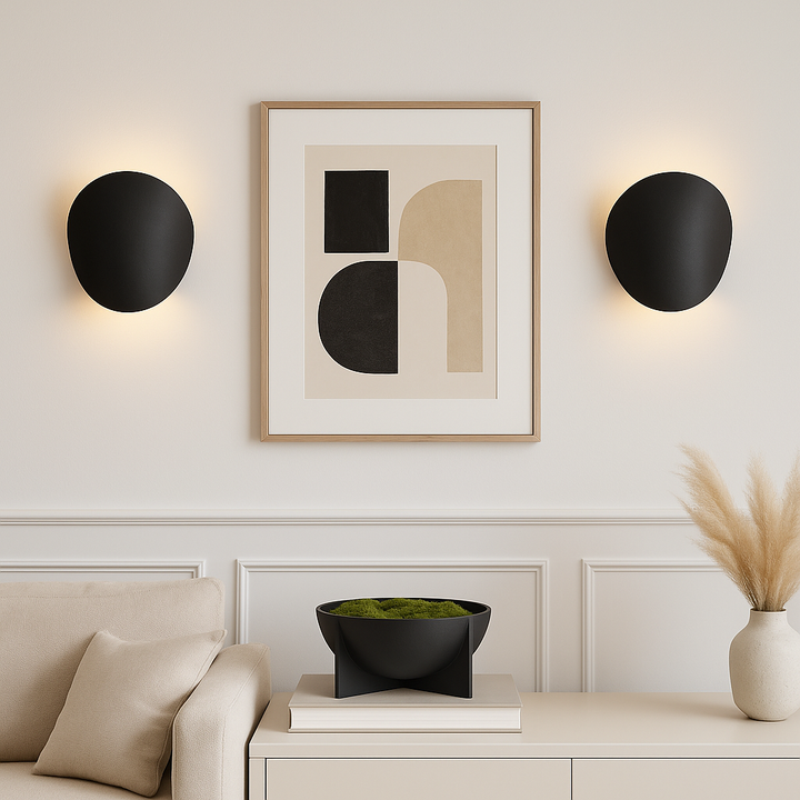 Pair of Delta black wall lights in a modern living room, framing abstract artwork above a sofa and console.