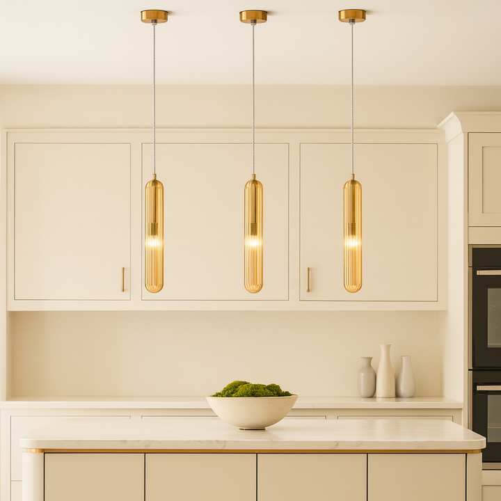 Set of three Florence gold ribbed glass pendant lights hanging above a luxury cream kitchen island with gold accents and a moss bowl centerpiece