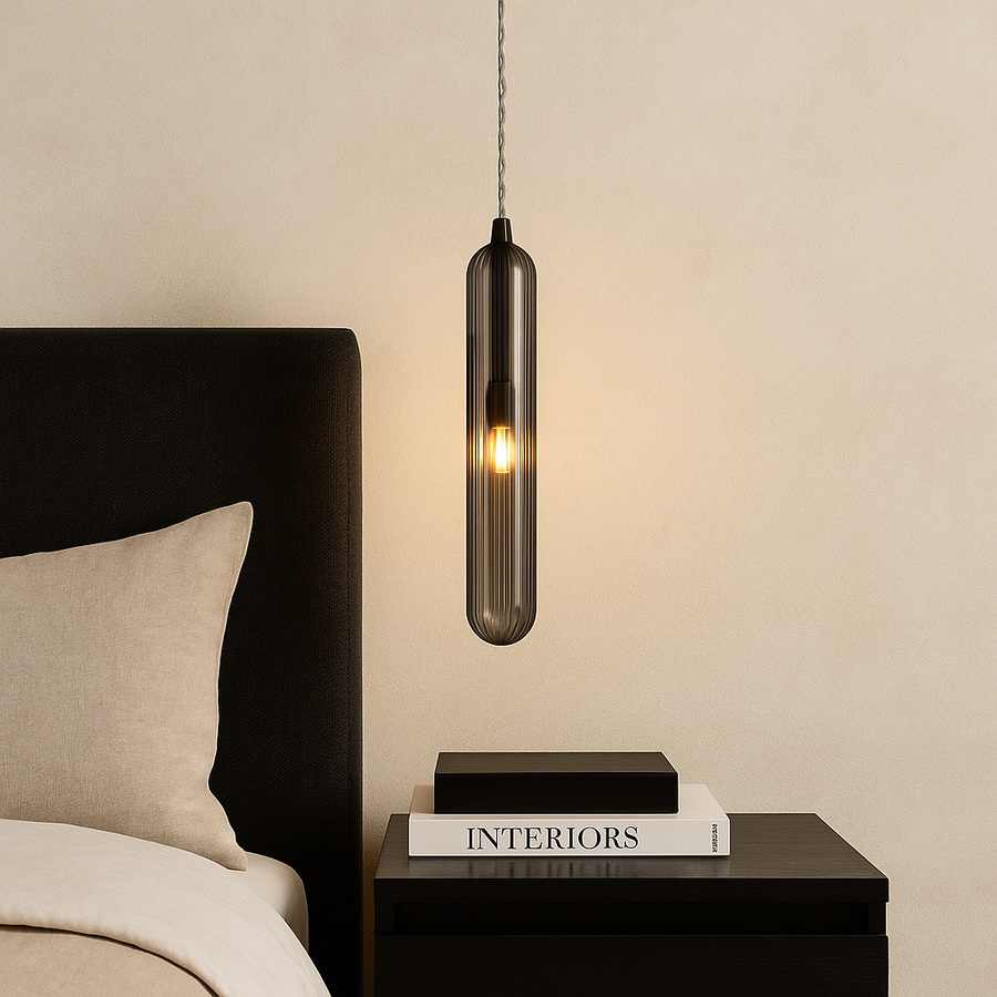 Florence smoked glass pendant light centred above a black bedside table with modern black and white styling books in a Nordic luxury bedroom