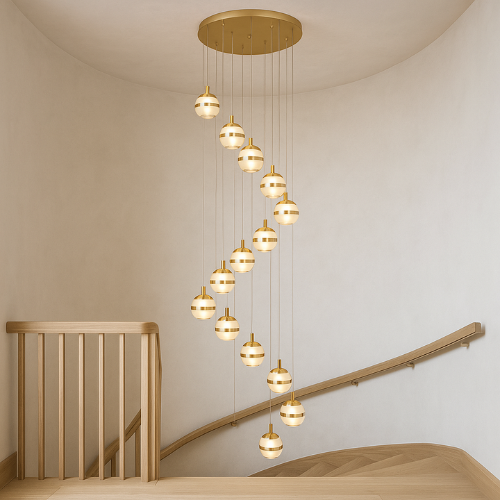 Large gold spiral pendant chandelier with glass globes styled in a light wood Scandinavian stairwell with neutral walls.