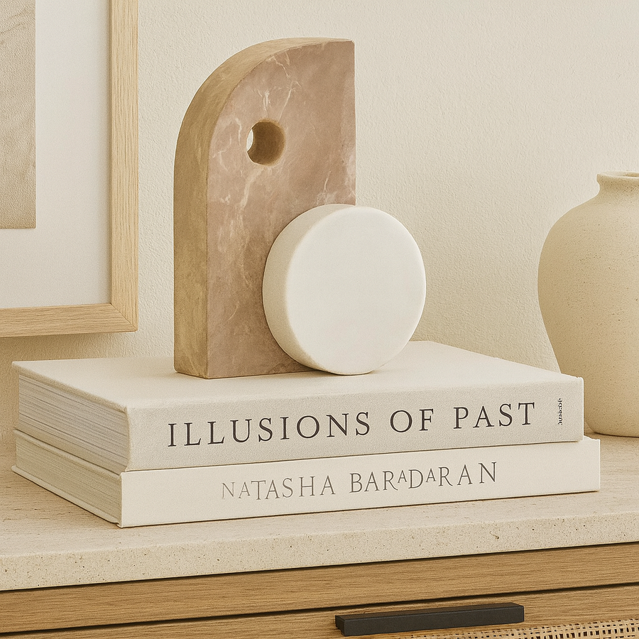 Geometric marble sculpture with circular accent styled on Nordic media wall unit, placed on design books with minimalist décor accessories.