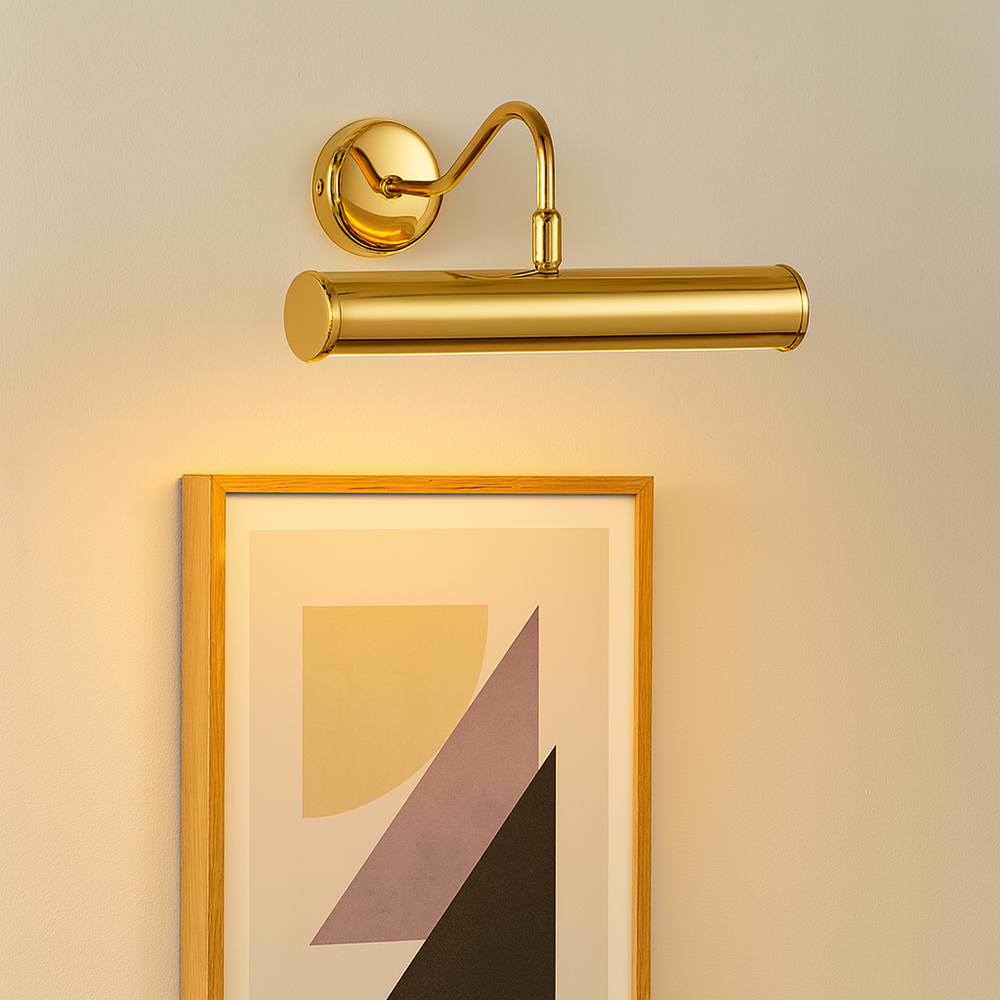 Polished gold picture wall light illuminating framed abstract geometric artwork on a neutral wall